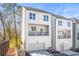New construction, three-story home features white siding, balcony, two-car garage and retaining wall in landscaped yard at 490 Hammons Way, Atlanta, GA 30315