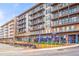 Apartment building with multiple units featuring balconies above restaurants with outdoor seating areas with colorful blue umbrellas at 490 Hammons Way, Atlanta, GA 30315