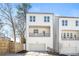 New construction, three-story home features white siding, balcony, two-car garage and retaining wall in landscaped yard at 490 Hammons Way, Atlanta, GA 30315