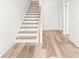 Bright hallway featuring light wood floors, white trim, and a staircase with wooden handrail at 490 Hammons Way, Atlanta, GA 30315