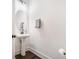 Stylish half bath features a pedestal sink, oval mirror, wood-look flooring, and crisp white walls at 211 N Auburn Landing Pl, Auburn, GA 30011