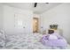 Comfortable bedroom with ceiling fan, carpet, large window, and a queen-sized bed with purple floral bedding at 211 N Auburn Landing Pl, Auburn, GA 30011