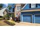 Close-up of a charming home, showcasing a stone facade, landscaped garden, and a two-car blue garage at 29 Sedgefield Overlook, Dallas, GA 30157