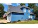 Rear exterior showcasing blue siding with a two-car garage; accented by landscaping and an American flag at 29 Sedgefield Overlook, Dallas, GA 30157