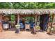 A secluded tiki bar area with thatch roof cover, wooden deck, and seating amidst a lush green backyard setting at 29 Sedgefield Overlook, Dallas, GA 30157
