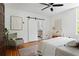 Bright bedroom featuring white walls, hardwood floors, ceiling fan, and sliding barn door to the ensuite bath at 694 Peeples Sw St, Atlanta, GA 30310