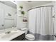 Well-lit bathroom with a gray-and-white shower curtain, floating shelves, and a framed print at 2140 Hurt Sw Rd, Marietta, GA 30008