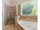 Bright bathroom with a glass-enclosed shower and a separate soaking tub by a window at 2832 Windrush Dr, Buford, GA 30518