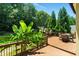 Wooden deck with dining table and chairs, banana plants, and an American flag in the landscaped backyard at 2832 Windrush Dr, Buford, GA 30518
