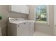 Laundry room equipped with a washer, dryer, and storage cabinets, next to window at 2832 Windrush Dr, Buford, GA 30518