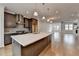 View of kitchen with stone island and stainless appliances opening to living area at 1273 Harvest Park Ln, Suwanee, GA 30024