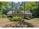View of the home's rear, featuring a sunroom with large windows and a small deck, surrounded by mature trees at 1252 Grist Mill Dr, Acworth, GA 30101