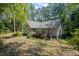 A view of the home's back, with the sunroom, a small deck and mature trees at 1252 Grist Mill Dr, Acworth, GA 30101