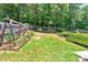 Lush backyard with a small garden, a wooden swing set, and a well-maintained lawn at 6236 Millstone Trl, Douglasville, GA 30135