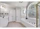Elegant bathroom featuring an arched window above the tub, a glass shower and double sinks at 6236 Millstone Trl, Douglasville, GA 30135