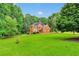 Beautiful two-story red brick home surrounded by lush greenery and an open front lawn at 2071 Habersham Cir, Covington, GA 30014