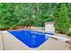 In-ground pool surrounded by a concrete deck, privacy fence, and lush trees at 2071 Habersham Cir, Covington, GA 30014