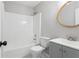 A clean, well-lit bathroom with a shower-tub combo, white toilet, and a round mirror at 5484 Denny Dr, Atlanta, GA 30349