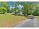 Exterior view of the house with a long driveway, expansive front lawn and lush trees at 14 Black Forest Run, Douglasville, GA 30134