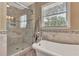 Bathroom with large soaking tub and glass enclosed shower with grey and white tiles at 522 Golfview Dr, Peachtree City, GA 30269