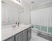This modern bathroom features a single sink vanity, a large mirror, and a shower with patterned shower curtain at 2019 Aldbury Ln, Woodstock, GA 30189