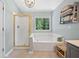 Bathroom featuring large soaking tub, glass shower, large window, neutral tile flooring, and decorative shelving at 2019 Aldbury Ln, Woodstock, GA 30189