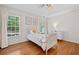 Bright bedroom features hardwood floors, a large window, white walls, and a comfortable bed with decorative pillows at 2019 Aldbury Ln, Woodstock, GA 30189