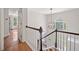 Bright hallway with hardwood floors, white railings, view of yard from large window, and an open doorway at 2019 Aldbury Ln, Woodstock, GA 30189