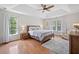 This primary bedroom features a tray ceiling, hardwood floors, two large windows, and is flooded with natural light at 2019 Aldbury Ln, Woodstock, GA 30189