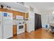 Bright kitchen includes white appliances, wood cabinets, and adjacent access to both the dining area and front entryway at 2030 Buford Dam Rd, Buford, GA 30518