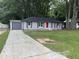 Exterior view of a brick home with a driveway and a detached garage showing the yard and mature trees at 8236 Tudor Dr, Jonesboro, GA 30238