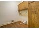 Small laundry room with wood cabinets and connections for washer and dryer at 1216 Valley Dr, Conyers, GA 30012