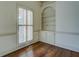 Cozy living room featuring hardwood floors, a built-in bookshelf, and natural light from shuttered windows at 1216 Valley Dr, Conyers, GA 30012