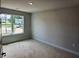 Bedroom with neutral walls and trim, a large window overlooking the neighborhood, and an electrical outlet at 305 Melanie Ct, Bowdon, GA 30108