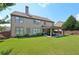 Exterior view of the back of the house, showcasing a large, level backyard, a covered patio and mature landscaping at 852 Van Briggle Path, Sugar Hill, GA 30518