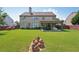 Back exterior featuring a spacious lawn, covered patio, and a fully fenced yard, offering privacy and outdoor living at 852 Van Briggle Path, Sugar Hill, GA 30518