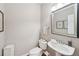 Well-lit half bath with a pedestal sink, decorative mirror, and wood flooring at 852 Van Briggle Path, Sugar Hill, GA 30518