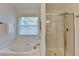 Spacious bathroom features a soaking tub, glass enclosed shower, and window at 335 Pintail Ct, Suwanee, GA 30024