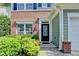 Close-up of the front entrance featuring a black door, brick accents, and lush green bushes at 335 Pintail Ct, Suwanee, GA 30024