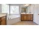 Bright bathroom features a soaking tub, wood cabinets and a large window bringing in plenty of natural light at 4765 Silver Leaf Dr, Cumming, GA 30040