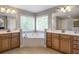 Bathroom featuring dual vanities, a corner bathtub, and large windows for ample natural light at 4765 Silver Leaf Dr, Cumming, GA 30040