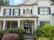 Elegant front entrance featuring a black metal and glass door, flanked by columns, black shutters, and lush greenery at 970 Tarpley Nw Rd, Kennesaw, GA 30152