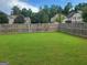 Large, fully fenced backyard with lush green grass and mature trees at 2424 Saint Andrews Rdg, College Park, GA 30337