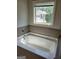 Relaxing bathtub with tile surround, offering a peaceful view from the window at 2424 Saint Andrews Rdg, College Park, GA 30337