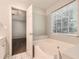 Bright bathroom features a soaking tub beneath a window and an open doorway at 230 Belmont Trl, Covington, GA 30016