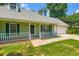 Inviting front porch with white railings, green siding, and a convenient attached two-car garage at 230 Belmont Trl, Covington, GA 30016