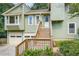 Green home with a two-car garage, wooden stairs leading to the front door, and manicured landscaping at 5093 Ravenwood Dr, Marietta, GA 30066