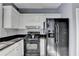 Charming kitchen featuring white cabinets, black countertops and appliances, and subway tile backsplash at 609 Bedford Court, Woodstock, GA 30188