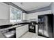 Charming kitchen featuring white cabinets, black countertops and appliances, and subway tile backsplash at 609 Bedford Court, Woodstock, GA 30188