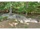 Landscaped backyard with stone patio under a canopy of mature trees, creating a tranquil outdoor space at 1590 Sunnybrook Farm Rd, Atlanta, GA 30350